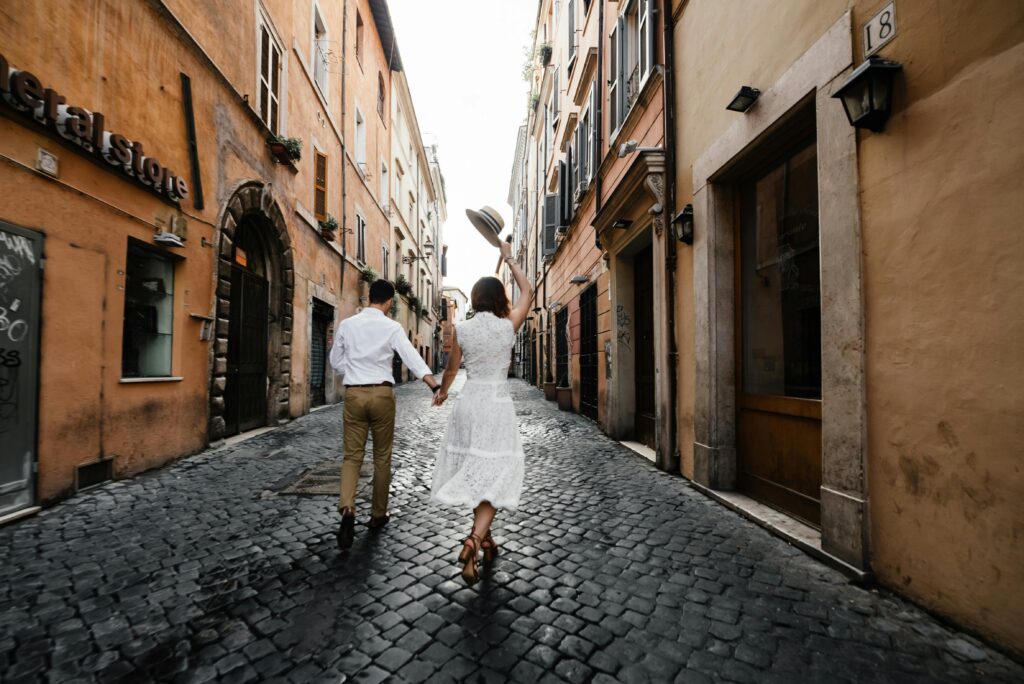 pexels photo 7973626 7973626 A couple holding hands and walking through a picturesque cobblestone street in an old town.